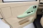 Crèmekleurig deurpaneel van de Scheelen Skyliner TS met mintgroene armsteun, chromen handgreep en ronde luidspreker.