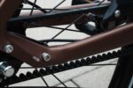 Close-up van de tandriem tussen de bruine framebuizen van de Levit Beleco Luxury Moccha.
