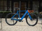 Blauwe Levit CAFE RIDER Ara e-bike van opzij, met hoge bovenbuis en oranje voordrager.