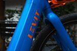 Accudeksel en oranje Levit-logo op het blauwe frame van de CAFE RIDER Ara.