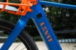 Bevestiging van de oranje voordrager aan het blauwe frame met Levit-logo.