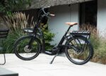 Zwarte Levit ZEN Obsidian e-bike met lage instap, voordrager en oranje zadel en handvatten.