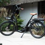 Zwarte Levit ZEN Obsidian e-bike met lage instap, voordrager en oranje zadel en handvatten.
