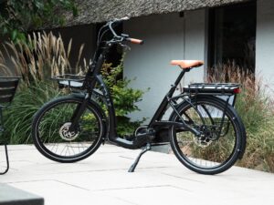 Zwarte Levit ZEN Obsidian e-bike met lage instap, voordrager en oranje zadel en handvatten.